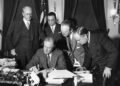 FBI Director J. Edgar Hoover stands behind President Franklin Delano Roosevelt and watches him sign a bill to enforce the fight against crime.